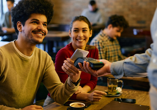 Happy couple making mobile payment at a restaurant.