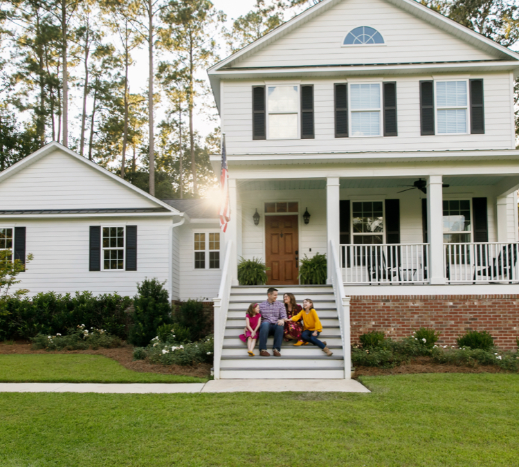 young family sitting on front steps of home